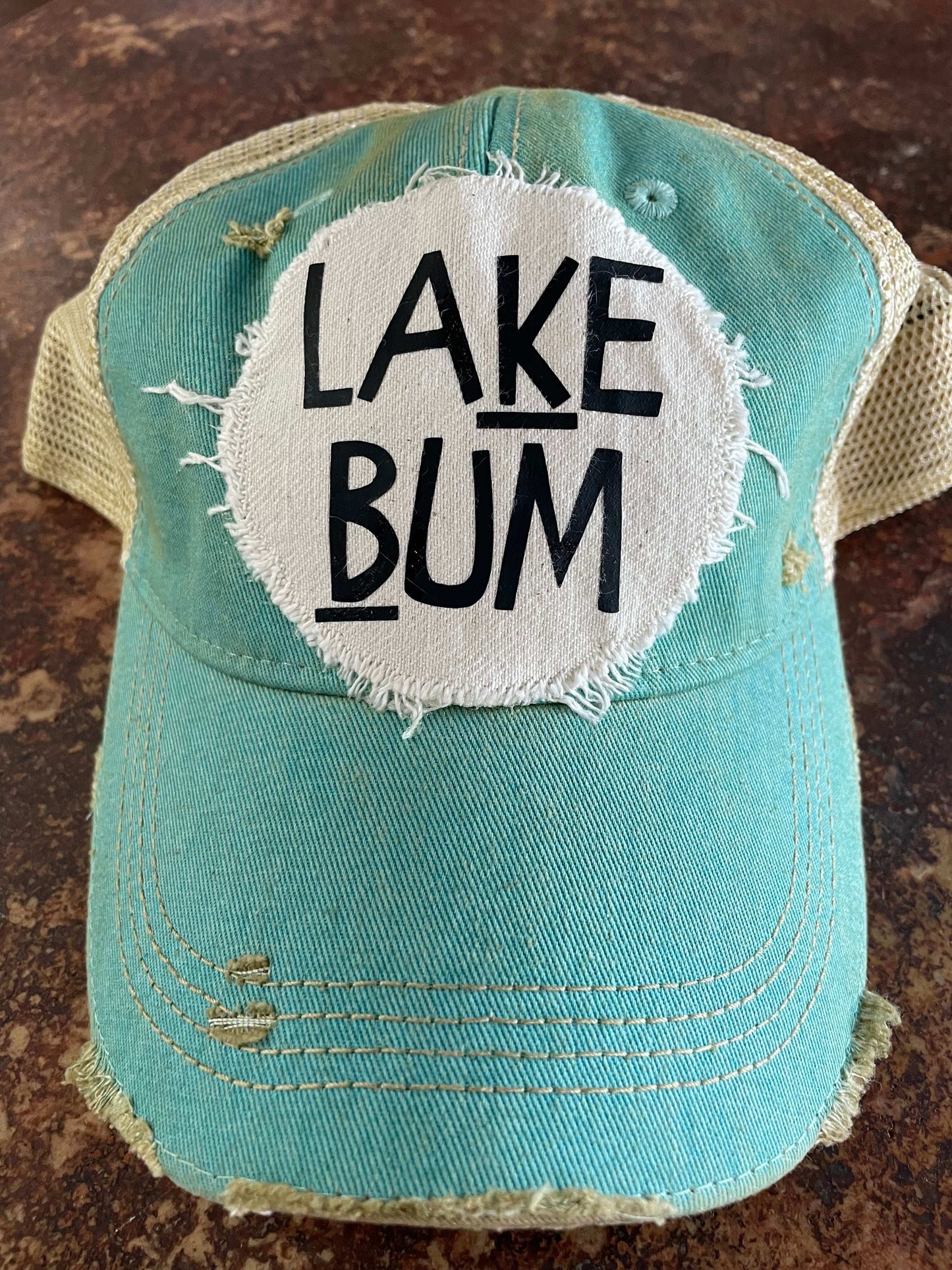 Blue cap with 'Lake Bum' patch on a textured surface