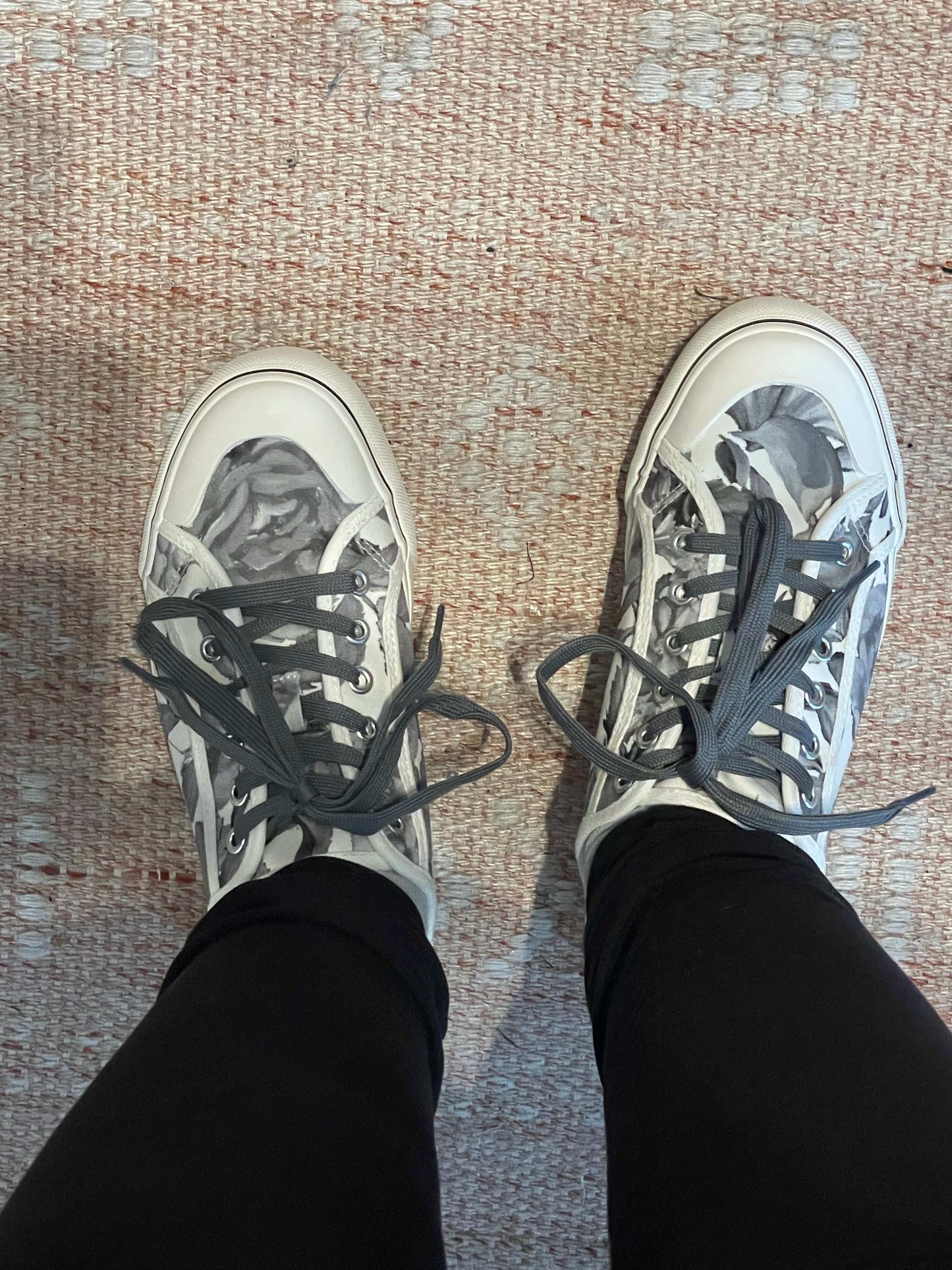 Person wearing black and white sneakers with gray laces