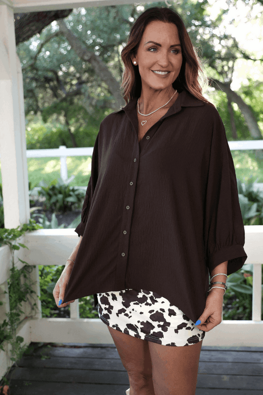 Woman wearing a brown shirt and cow print skirt outdoors
