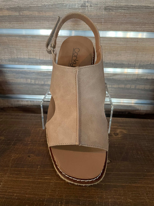 Beige sandal on a clear stand against a wooden wall.