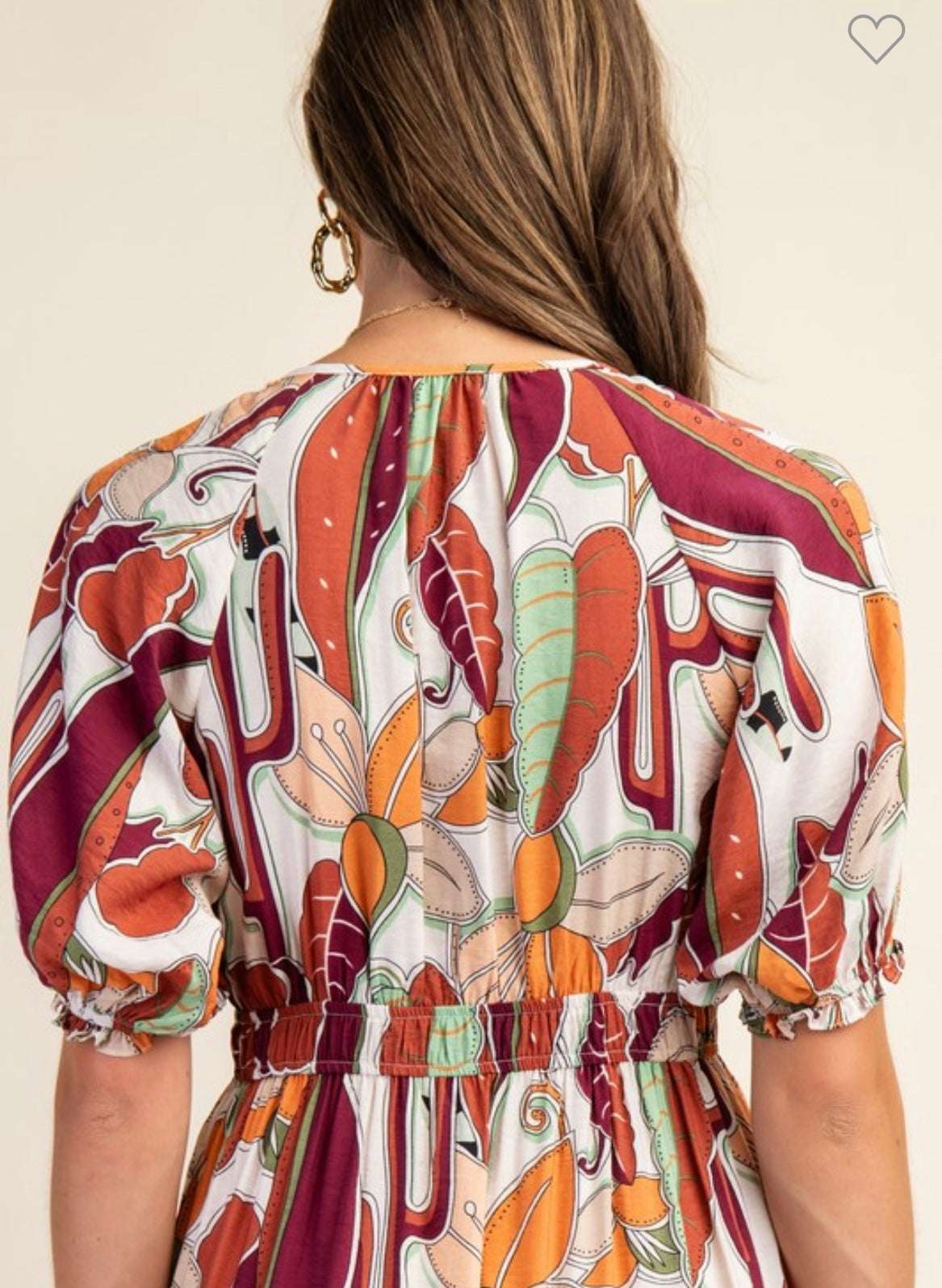 Woman wearing a colorful patterned dress with a neutral background