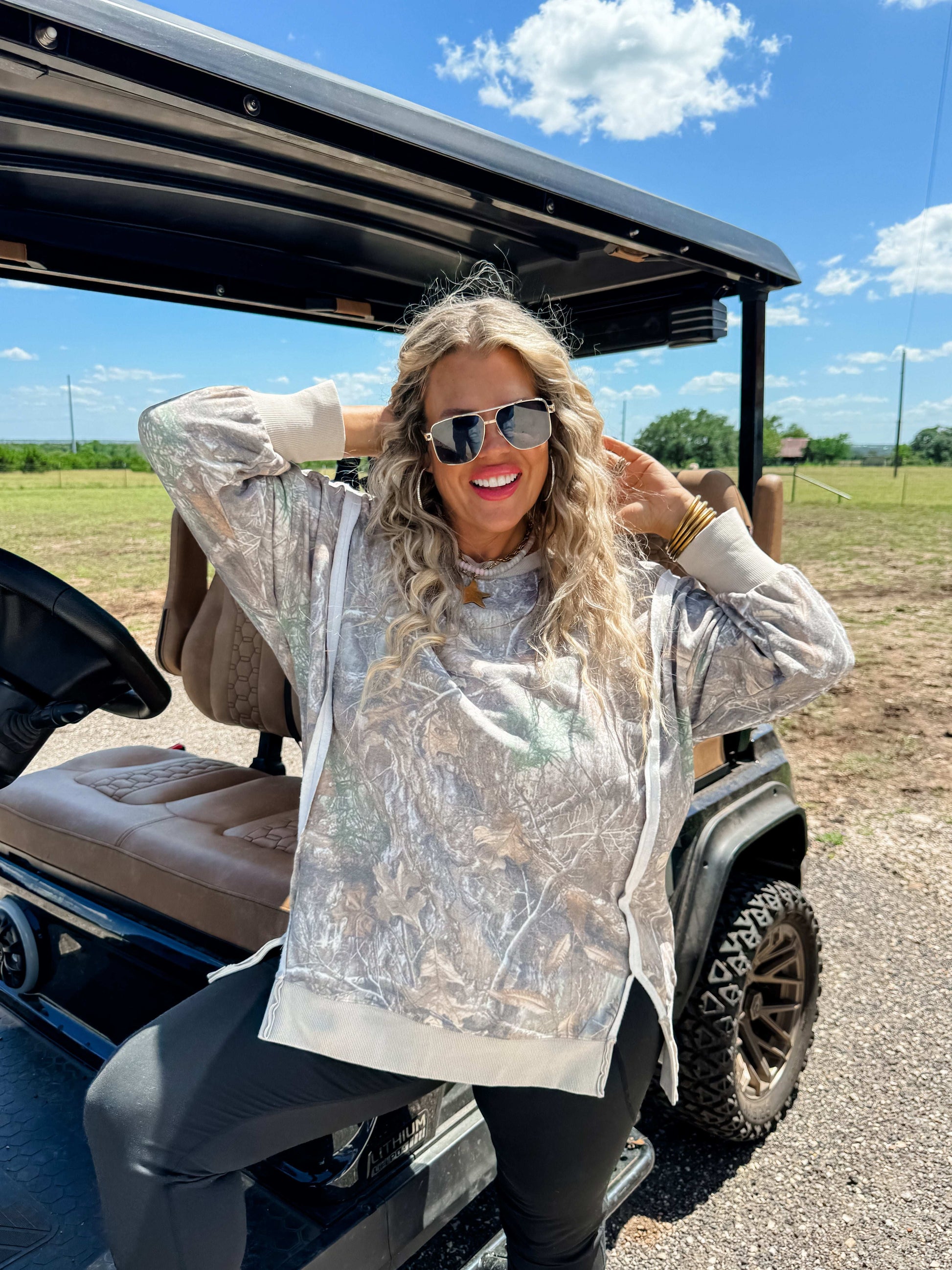 Woman in a camouflage sweatshirt sitting in a golf cart