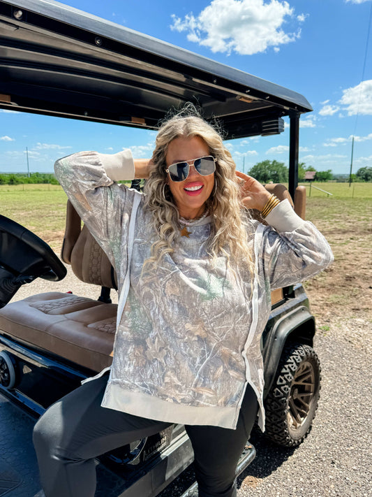 Woman in a camouflage sweatshirt sitting in a golf cart