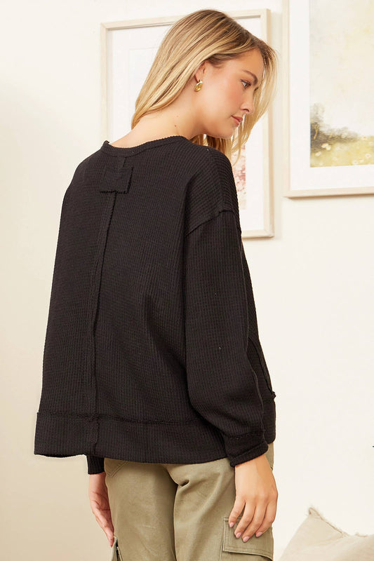 Woman wearing a black sweater in a room with framed pictures on the wall.