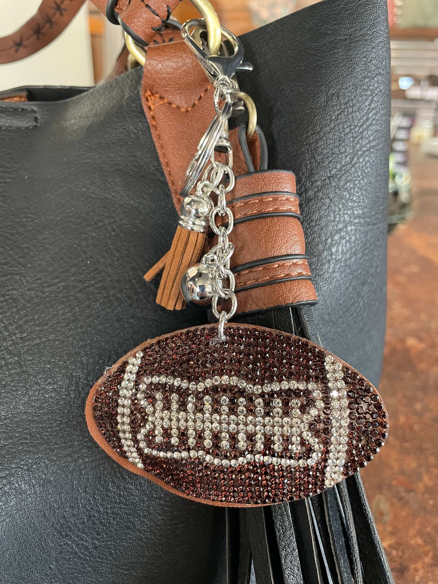 Sparkly football-shaped purse charm and key chain with metallic accents, perfect for game day style
