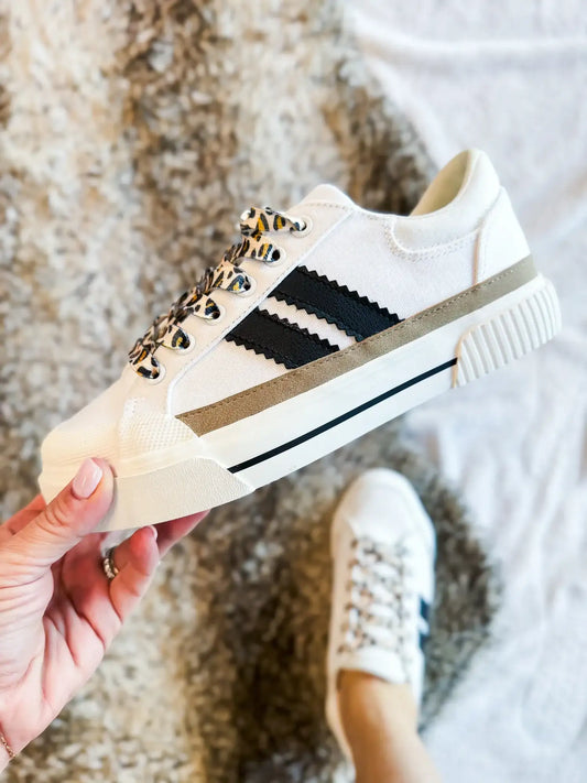 White sneaker with black stripes and leopard-print laces, featuring cushioned insole and easy lace-up closure for all-day comfort and trendy flair