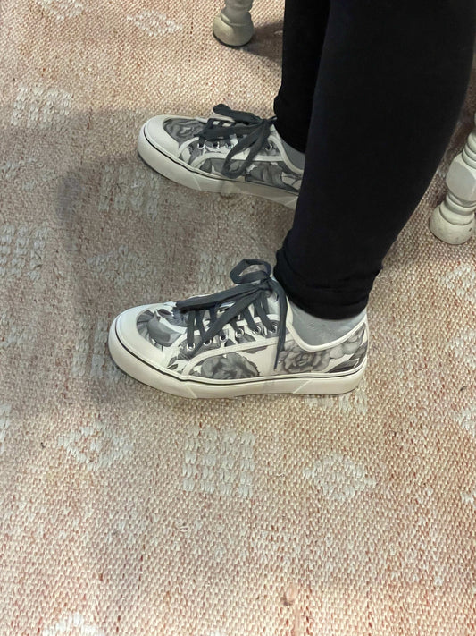 Person wearing black and white sneakers on a textured beige carpet