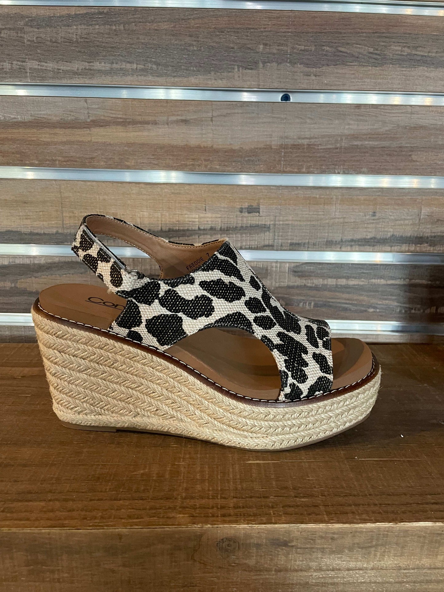 Wedge sandal with leopard print strap on a wooden surface