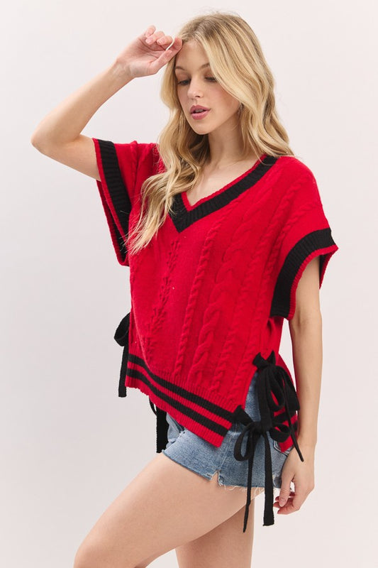 Woman wearing a red and black top with denim shorts on a white background