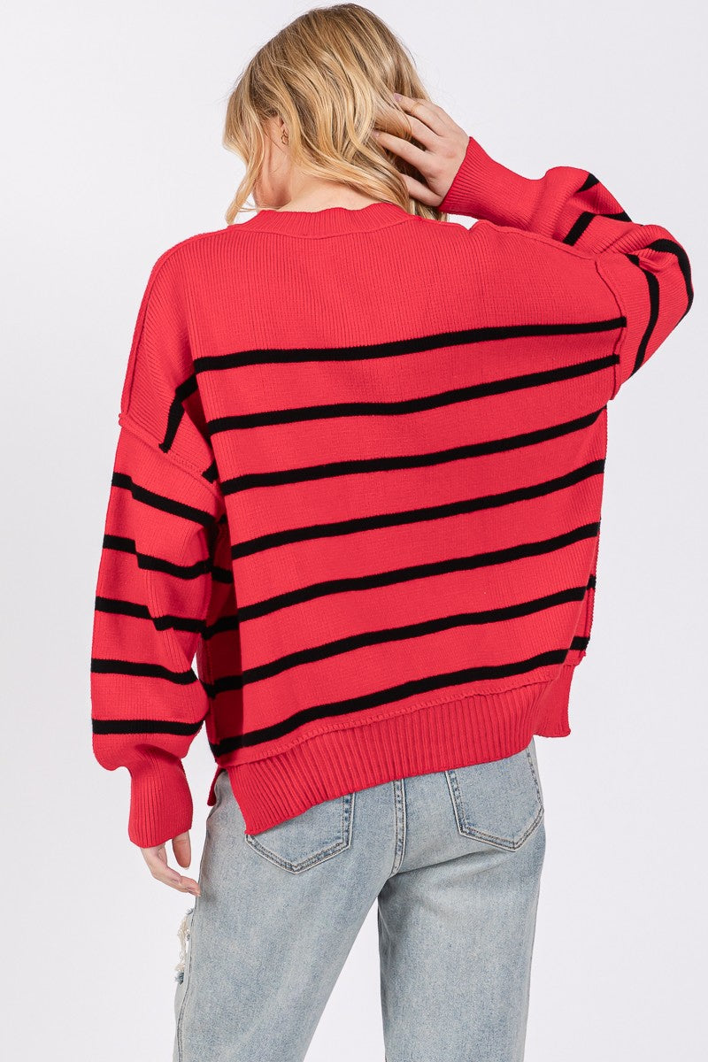 Person wearing a red sweater with black stripes and light blue jeans on a white background
