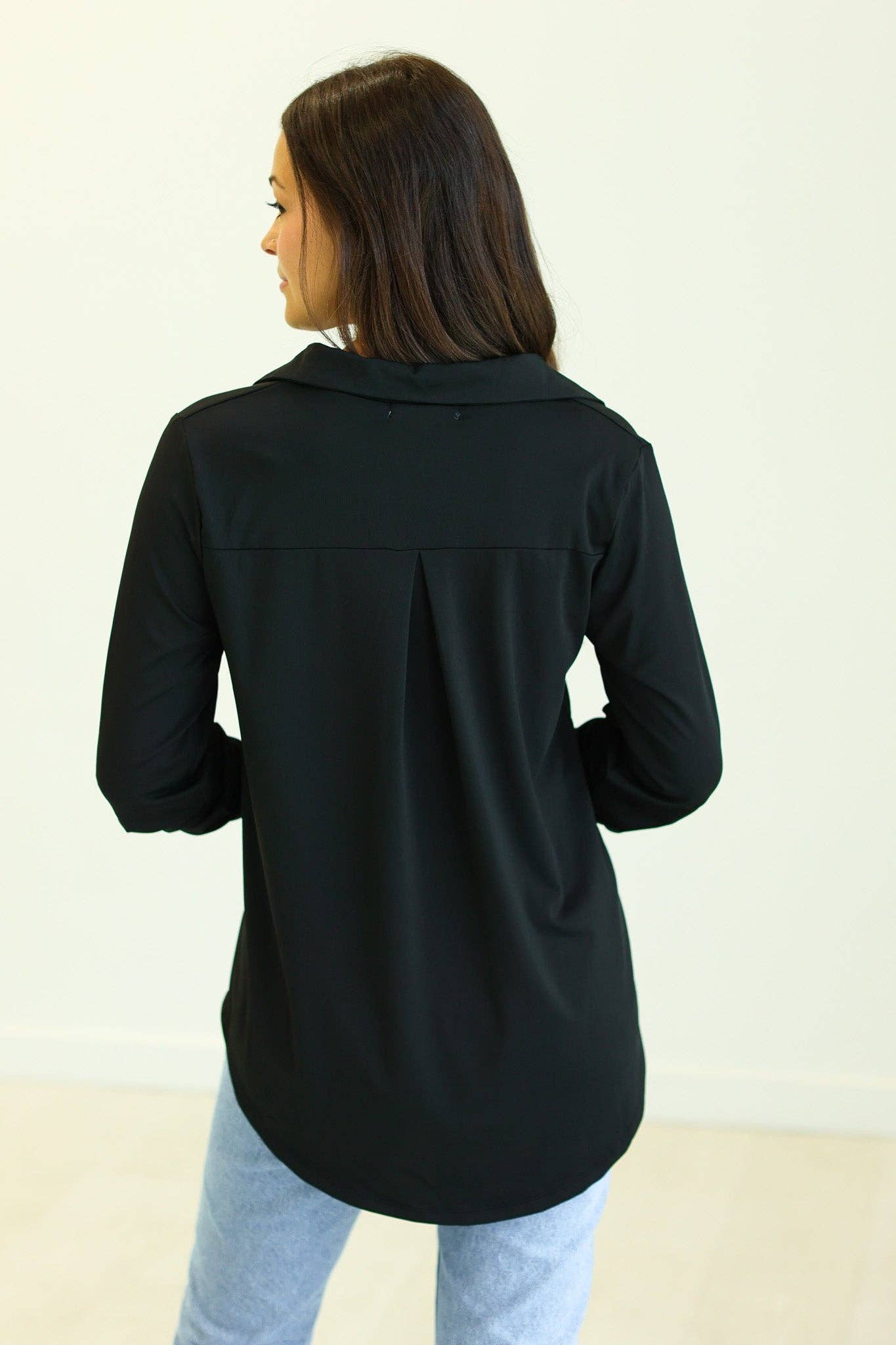 Black V-neck top with relaxed fit, high-stretch fabric, and adjustable sleeves—wear rolled or long for a customizable, polished everyday look, back view