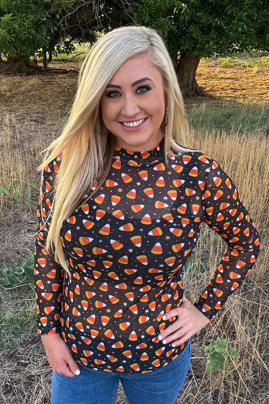 Woman wearing a black long-sleeve mesh top with orange candy corn pattern