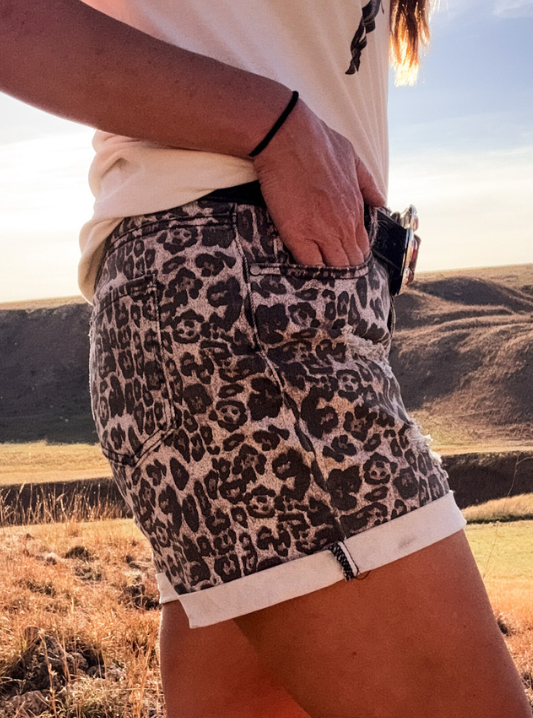 Person wearing leopard print shorts in a desert landscape