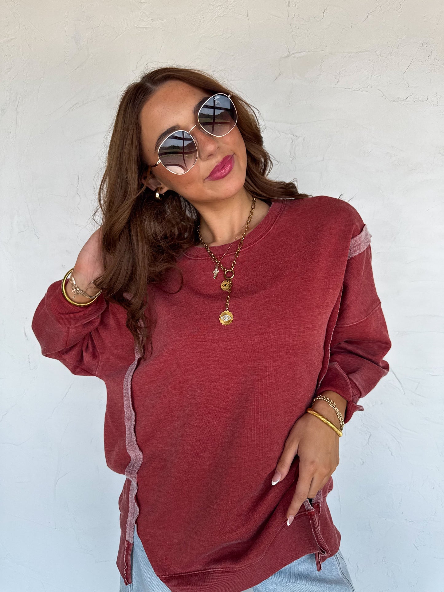 Woman wearing a red sweater with sheer sleeves against a white background