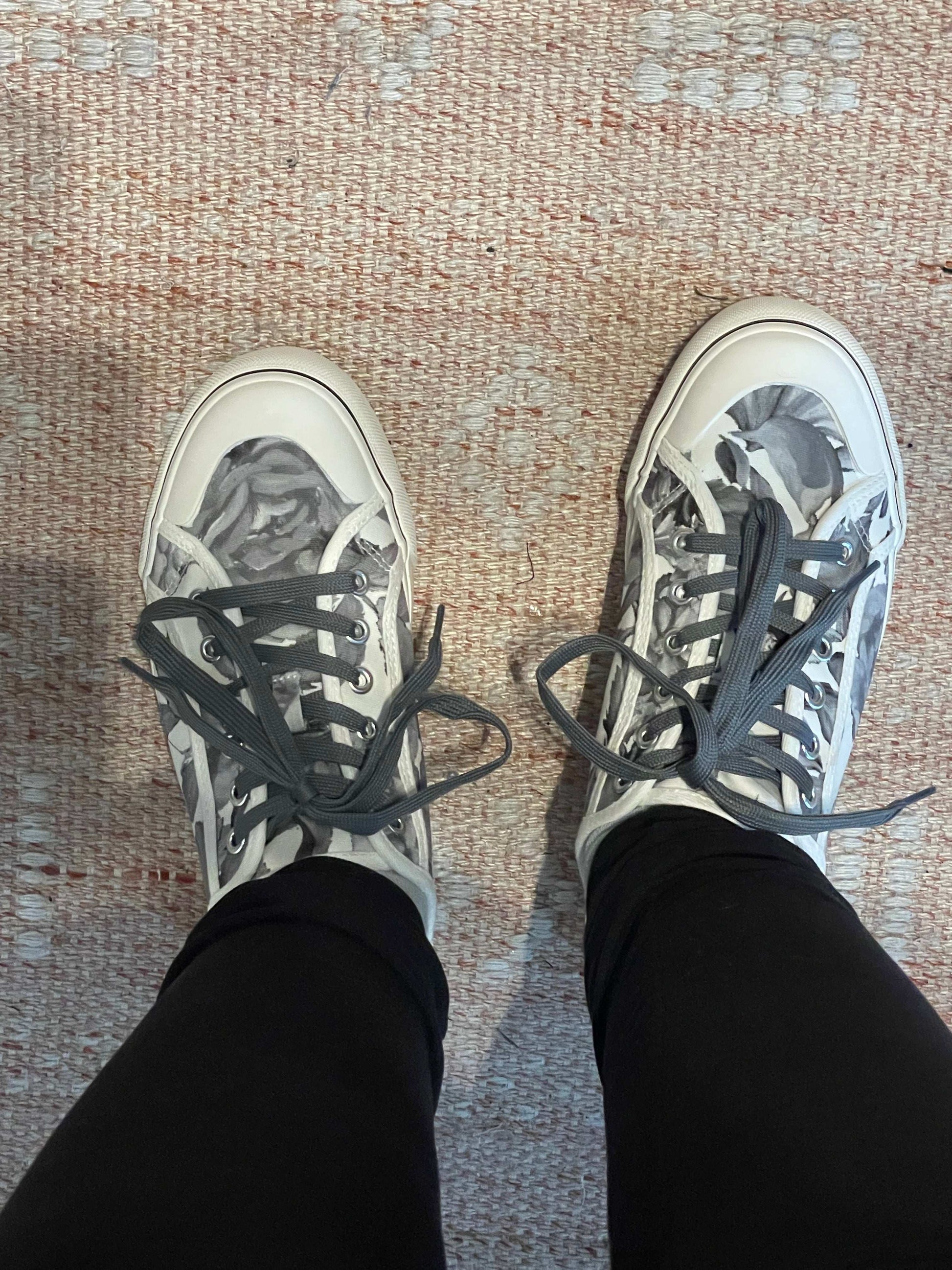 Person wearing black and white sneakers with gray laces