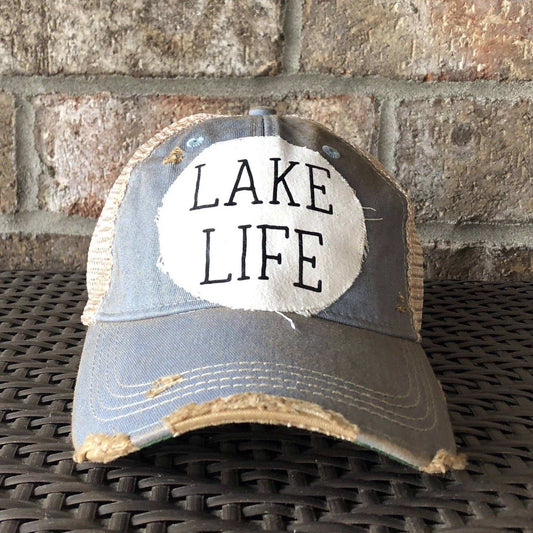 Trucker hat with 'Lake Life' text on a stone surface