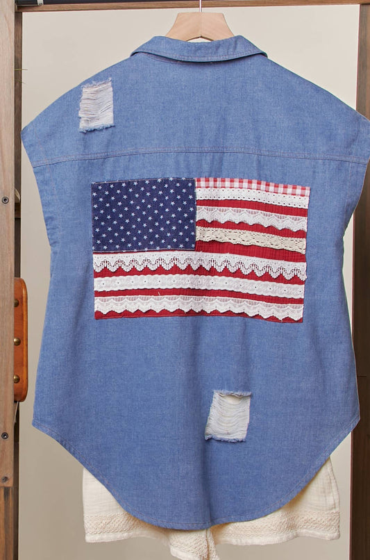 Blue denim shirt with American flag patch on a wooden rack.