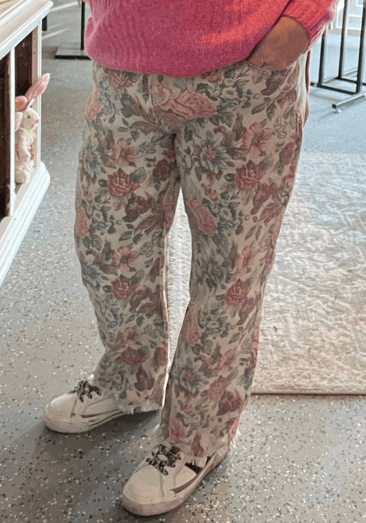 Person wearing floral pants and a pink sweater in an indoor setting