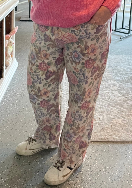 Person wearing floral pants and a pink sweater in an indoor setting