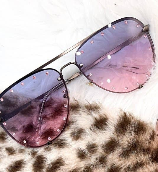 Pair of sunglasses with pink lenses on a leopard print surface