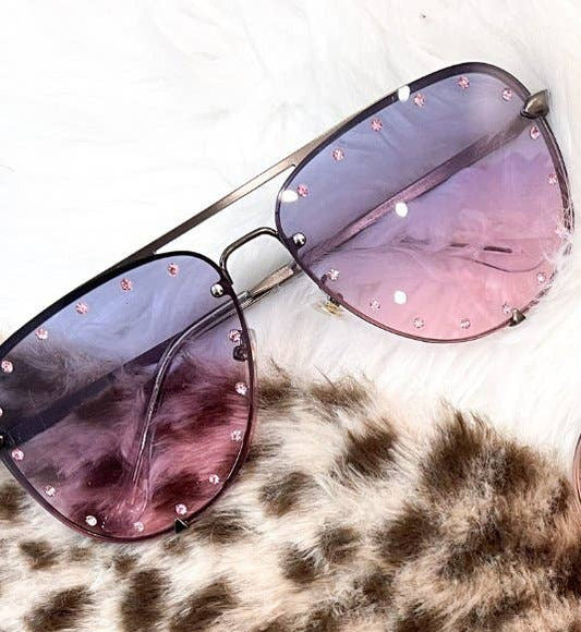 Pair of sunglasses with pink lenses on a leopard print surface