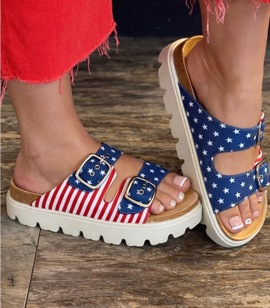 Flag-patterned sandals on a wooden floor