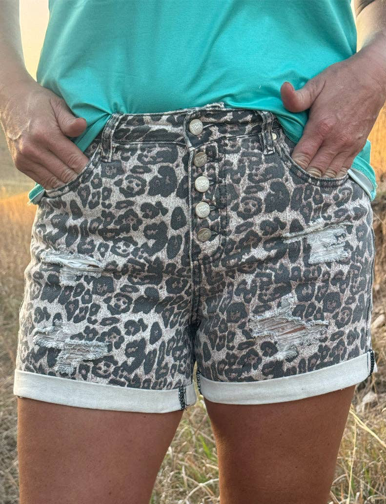 Person wearing leopard print shorts and a turquoise top in an outdoor setting