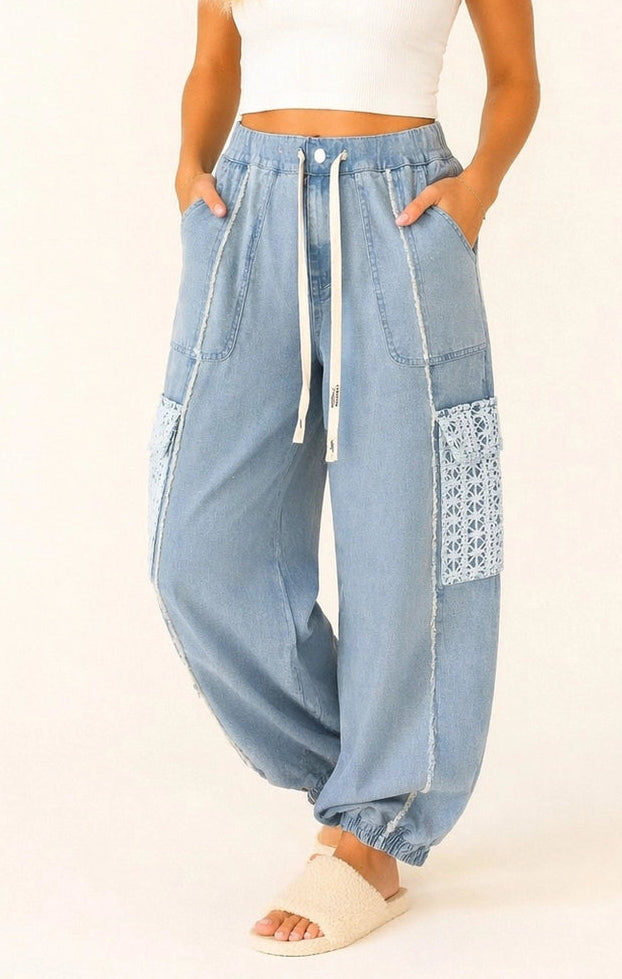 Woman wearing light blue high-waisted pants with a white top on a beige background