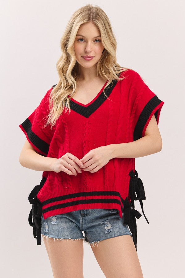 Woman wearing a red sweater with black trim on a plain background