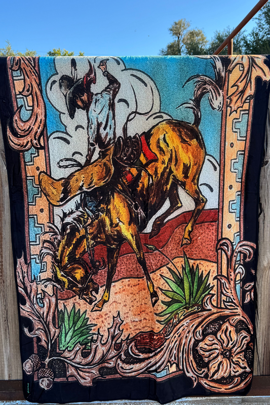 Decorative blanket with a bull and rider design on a wooden surface.